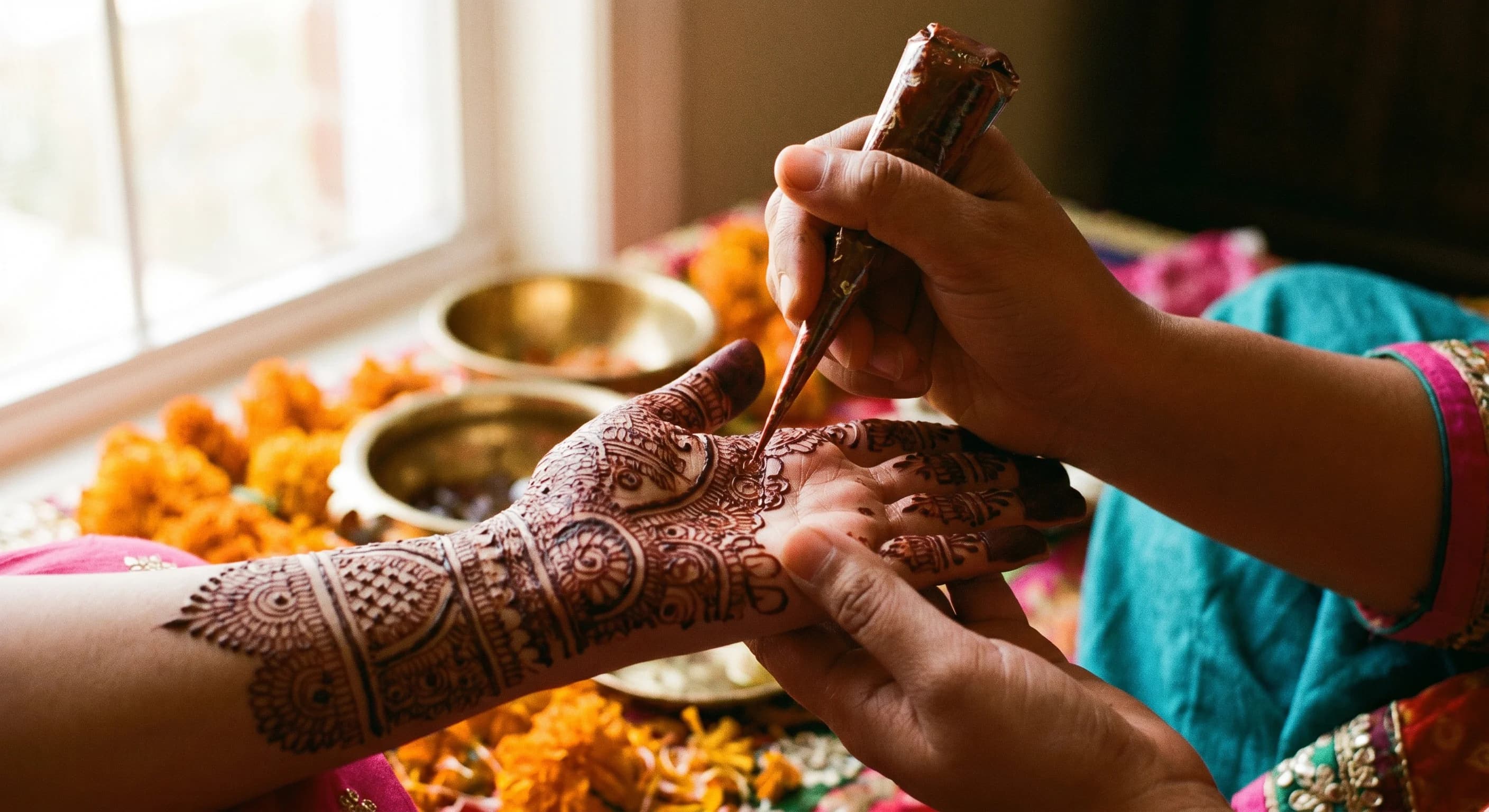 Close-up of hands receiving intricate fresh mehndi henna designs before a wedding celebration